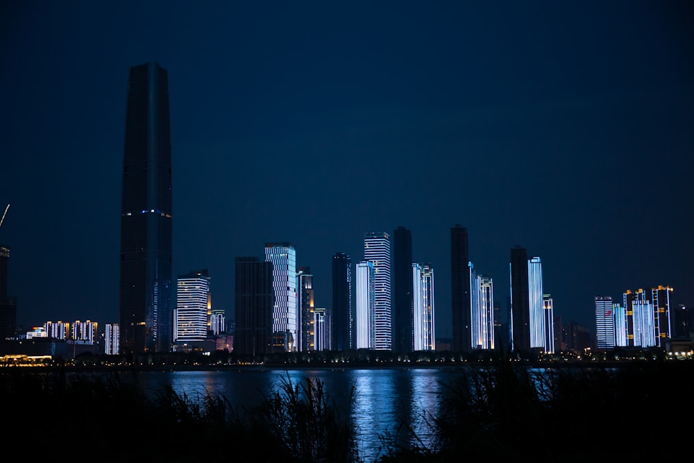 Una ciudad de noche con un cuerpo de agua frente a ella