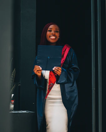 A smiling student holding a dual diploma certificate in front of an American high school.