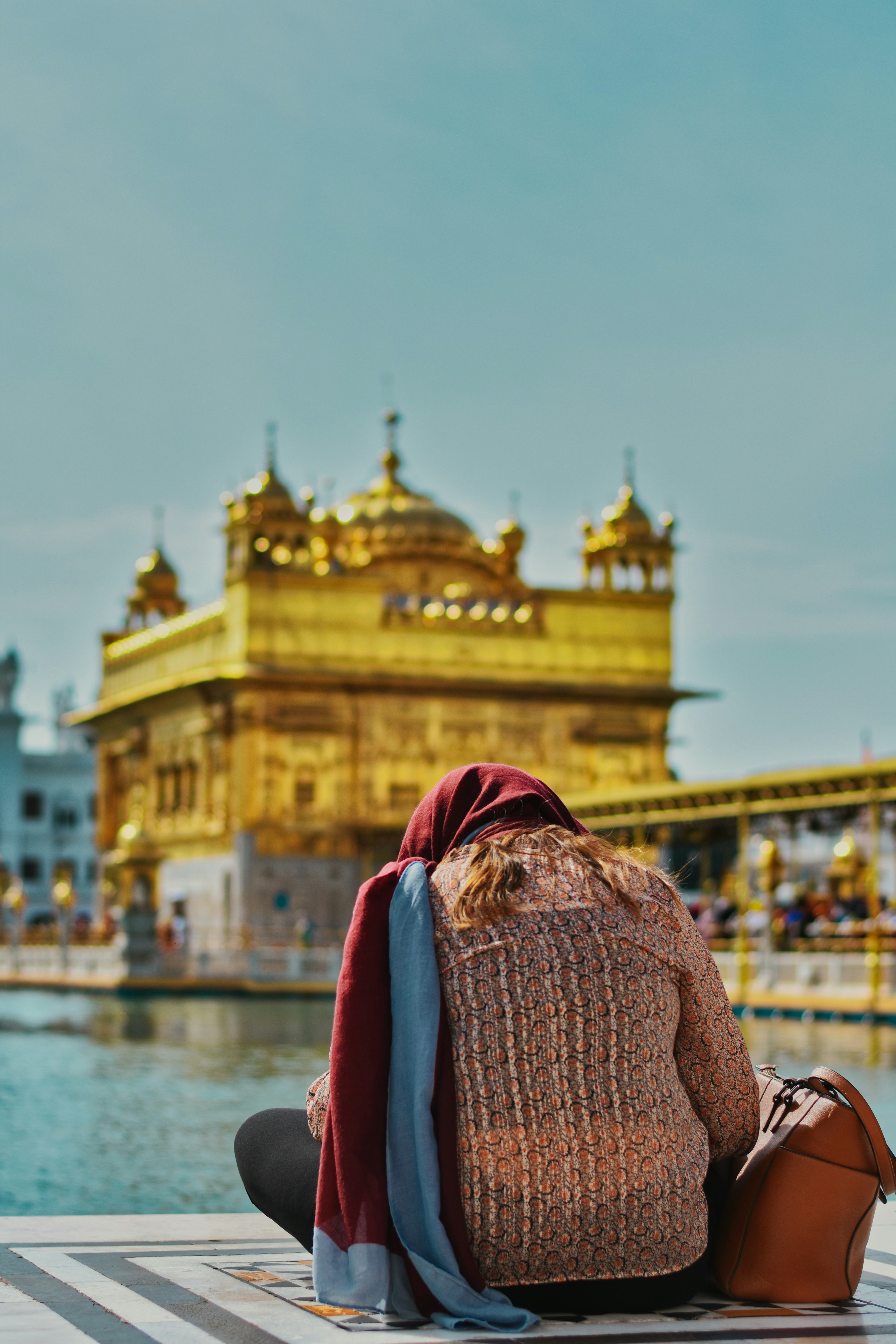 a woman sitting on the ground in front of a body of water