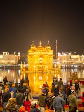 Volunteers distributing prasad to devotees under the golden temple dome bathed in soft sunlight.