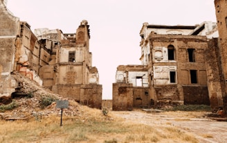 an abandoned building with a sign in the foreground