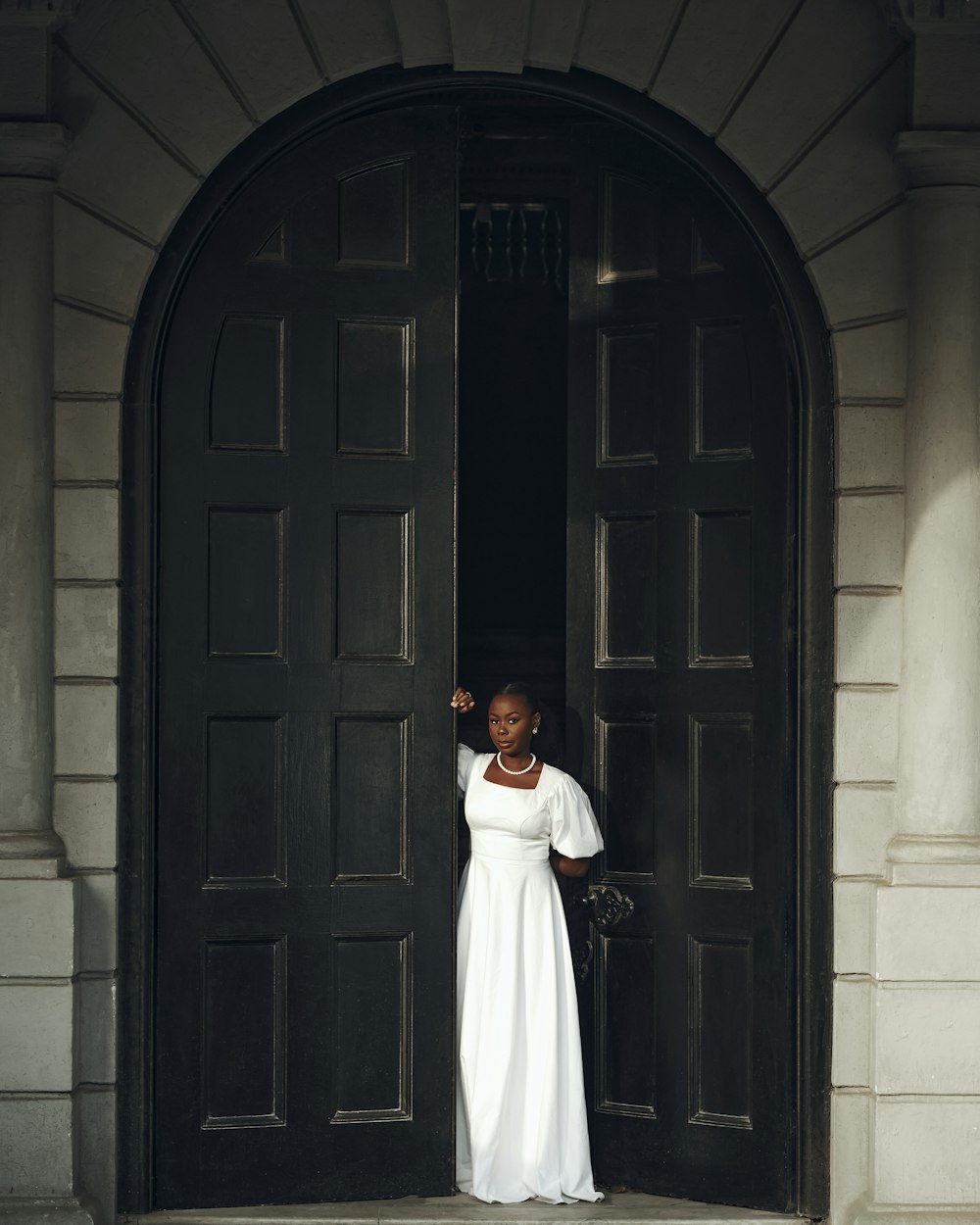 a woman in a white dress standing in a doorway