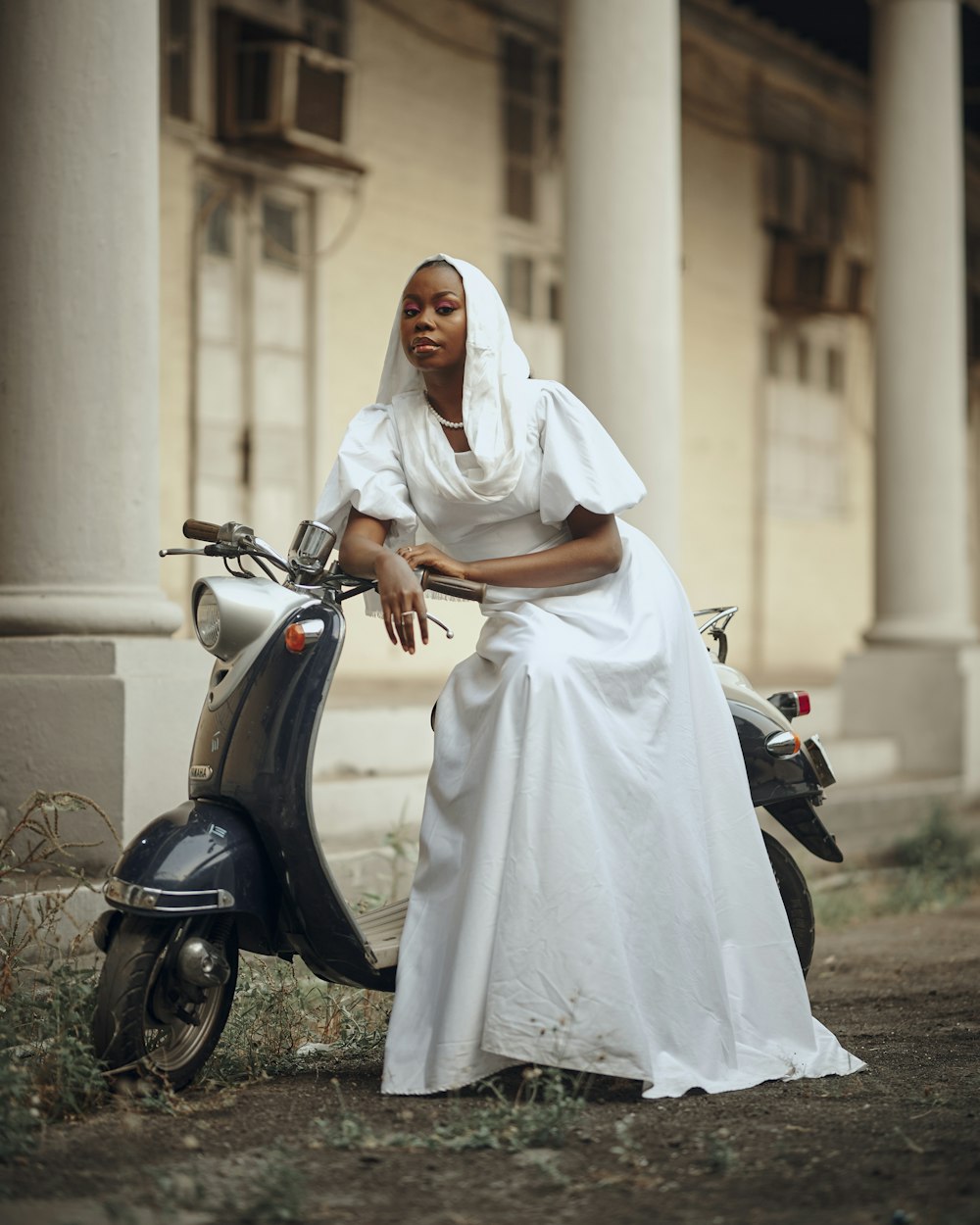 a woman in a white dress sitting on a scooter