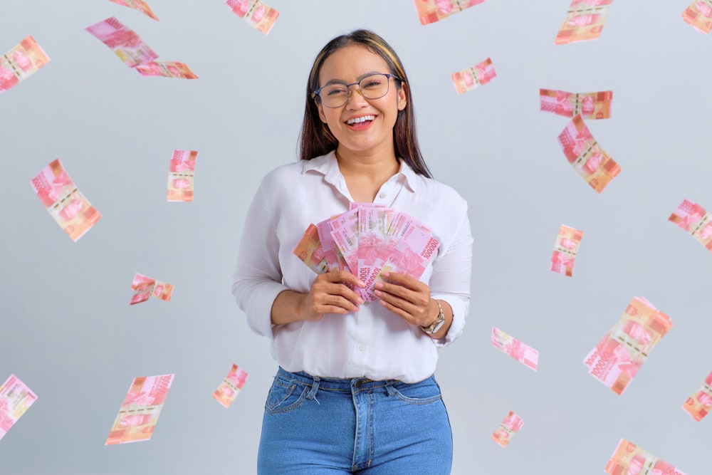 a woman is holding a fan of money