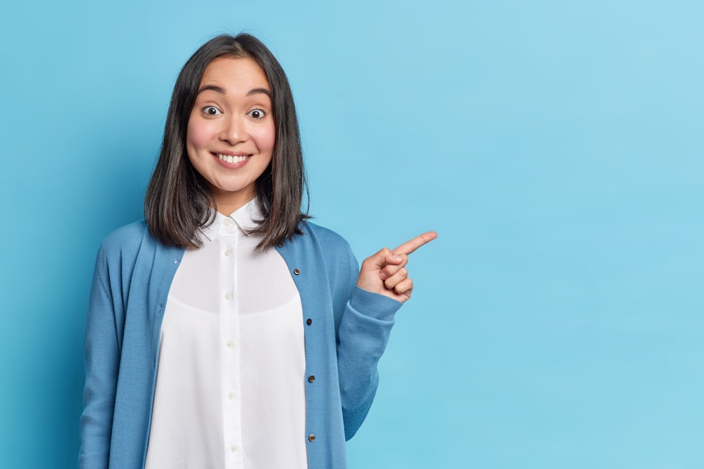 a woman in a blue cardigan pointing to the side