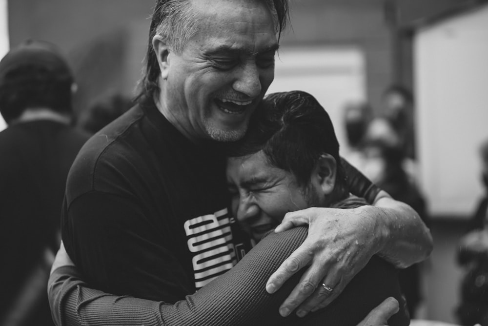 two men hugging each other in a room