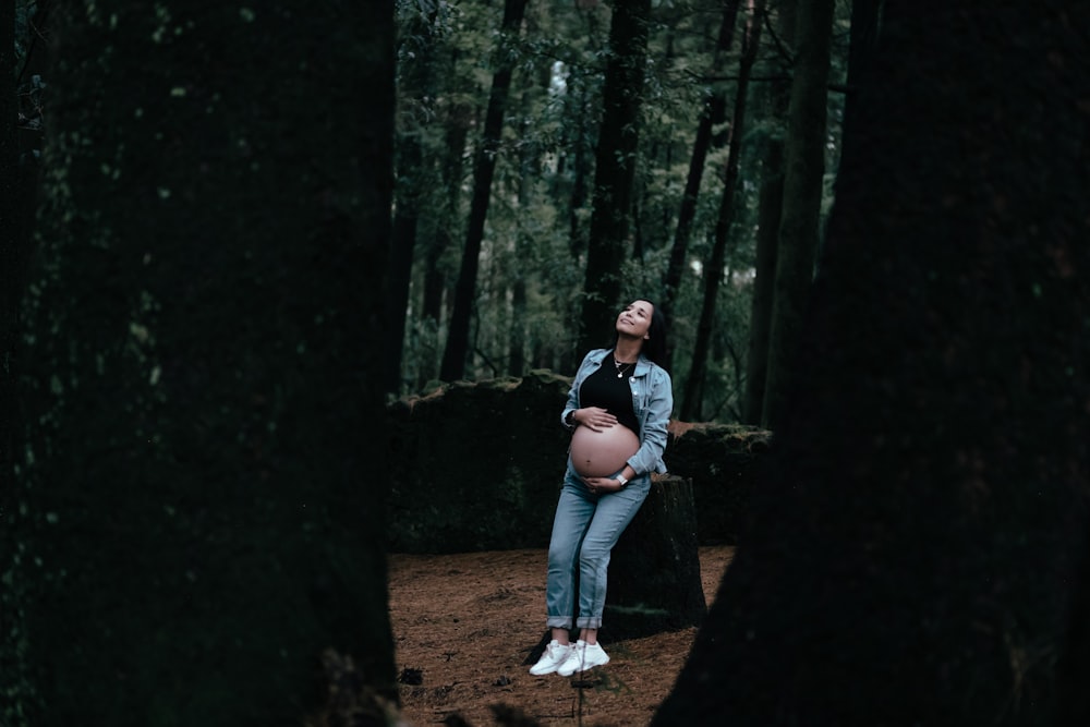 a pregnant woman standing in the woods with her belly exposed