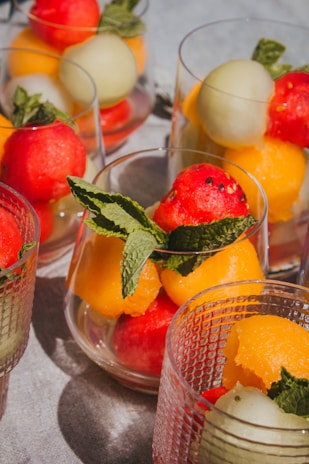 Colorful fruit sorbet balls artistically arranged on a white plate with mint leaves.