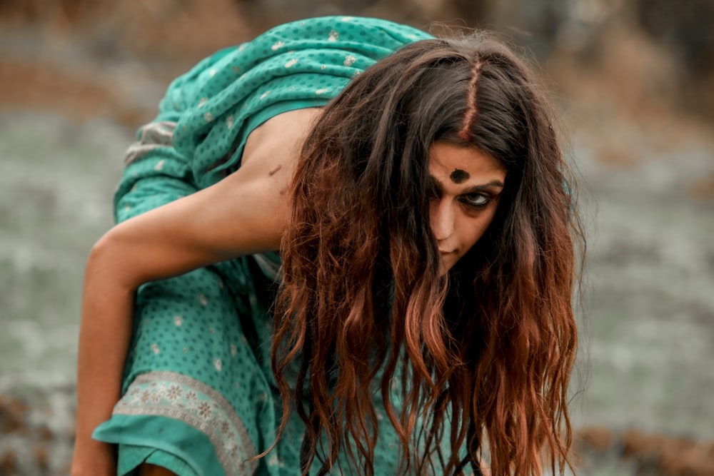 a woman with long hair is bending over