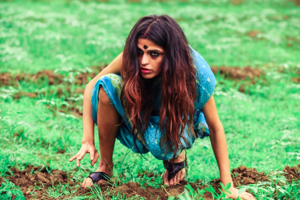 a woman kneeling down in the middle of a field