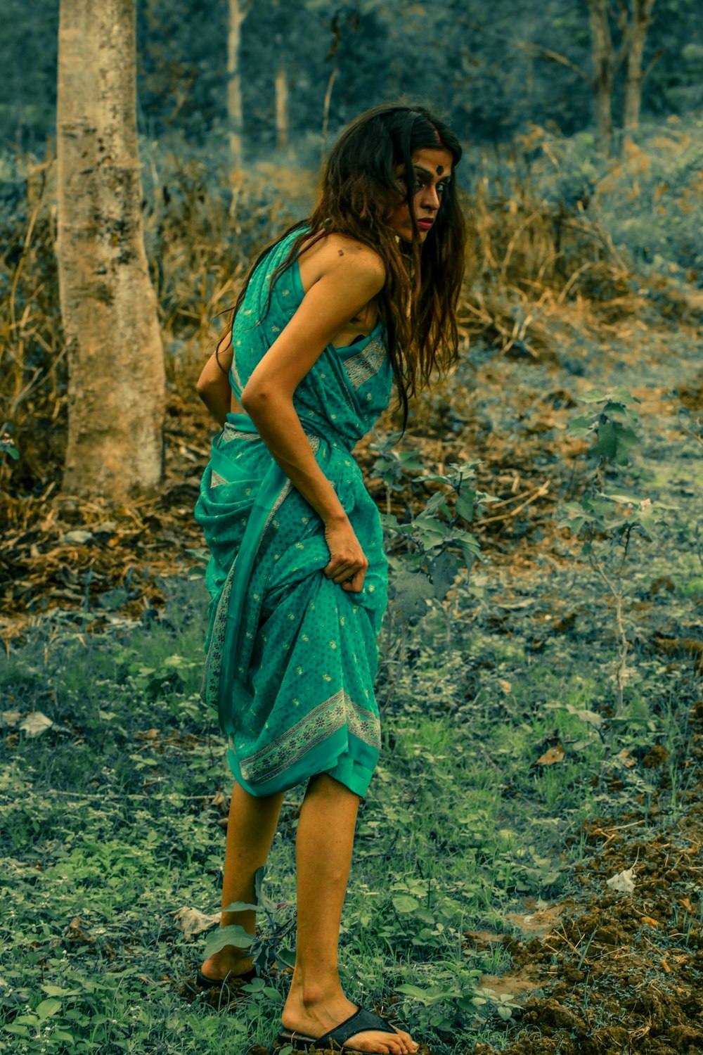a woman in a green dress standing in a forest