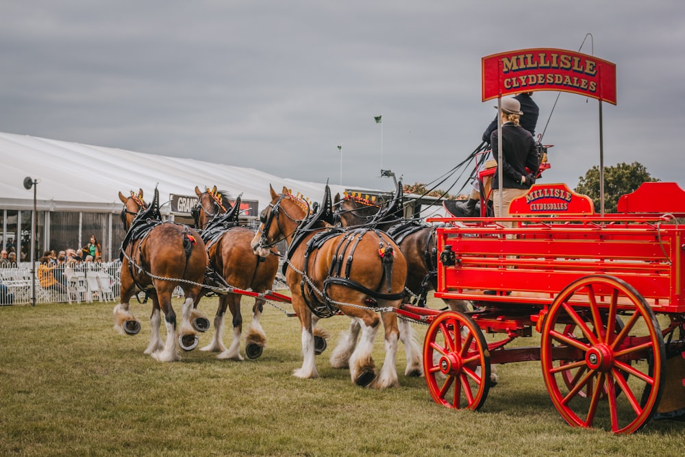 a group of horses pulling a red wagon