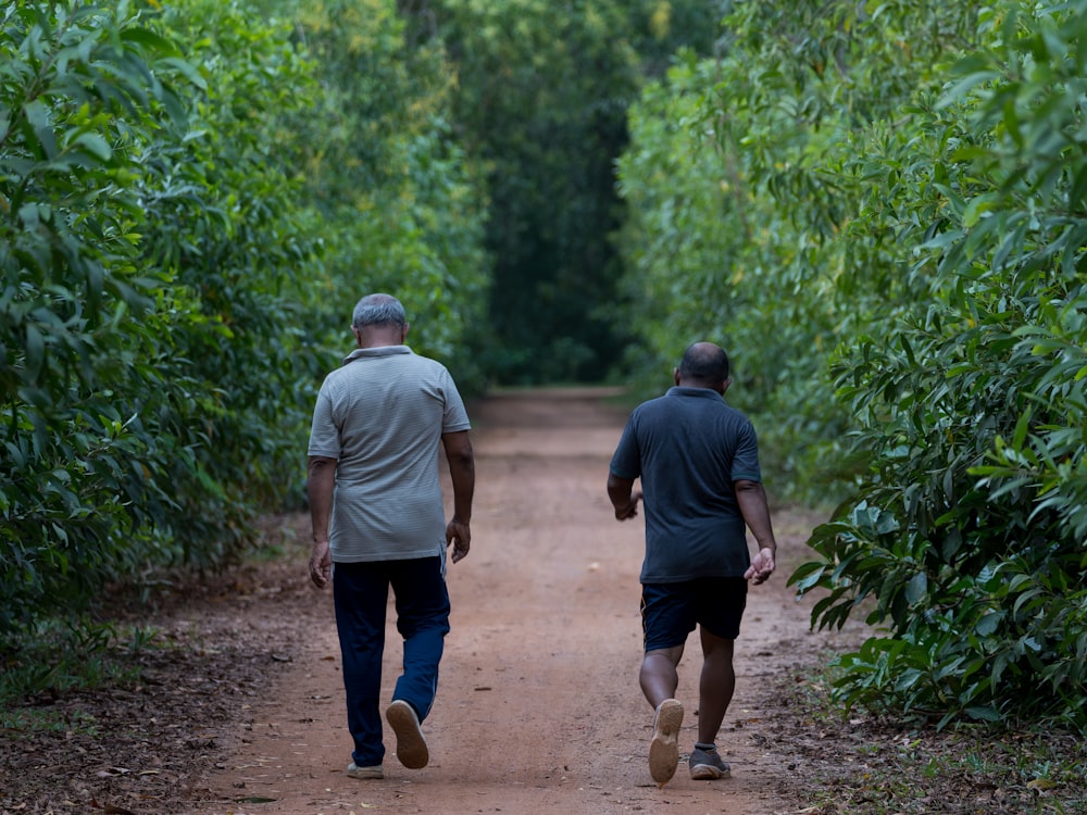 a couple of men walking down a dirt road