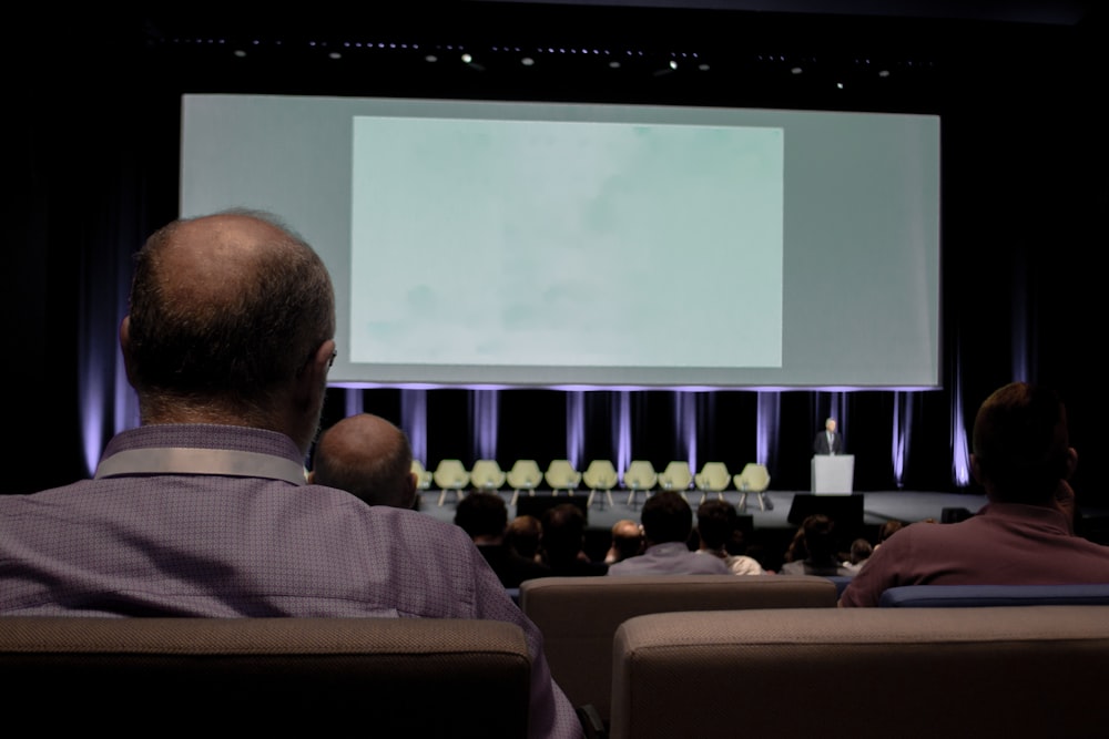 a group of people sitting in front of a projection screen