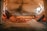 Two pizzas are being cooked inside a traditional wood-fired oven. Flames and embers surround the pizzas, creating a warm and rustic atmosphere. The oven is made of stone, and the pizzas are topped with various ingredients such as pepperoni and vegetables.