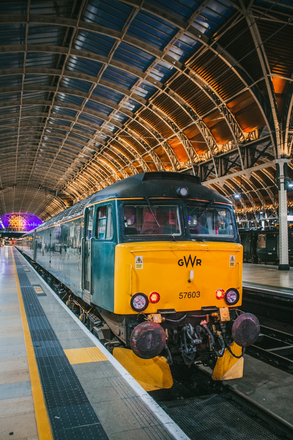 a yellow and green train pulling into a train station