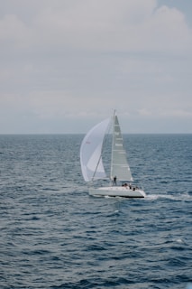 a sailboat with a white sail on a body of water
