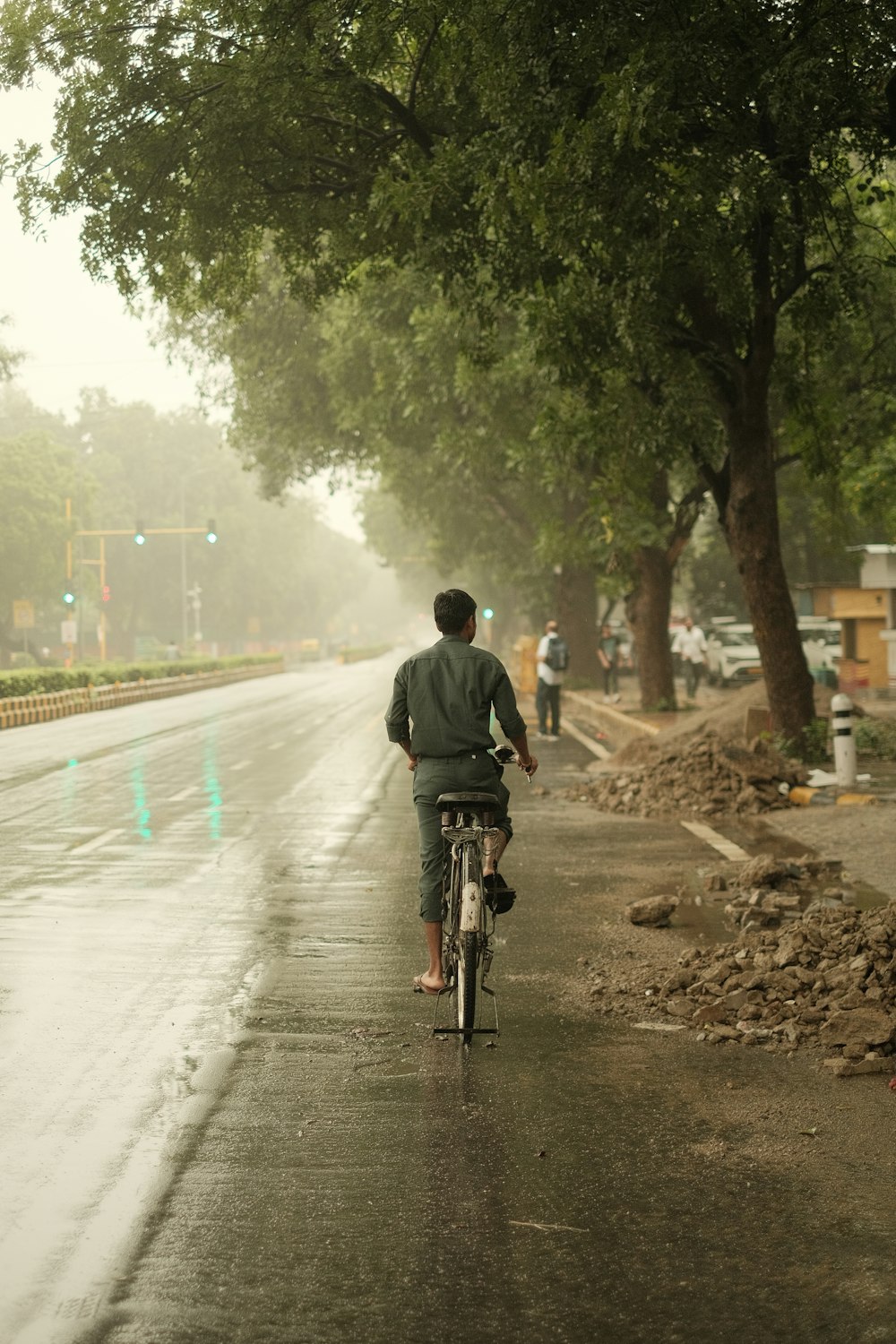 Un homme à vélo dans une rue détrempée par la pluie