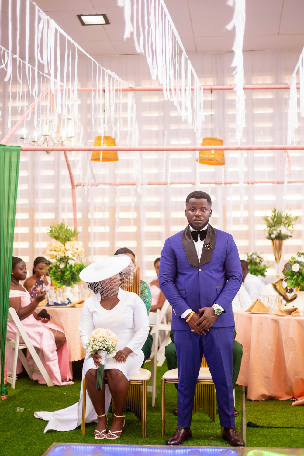 a man in a purple suit standing next to a woman in a white dress