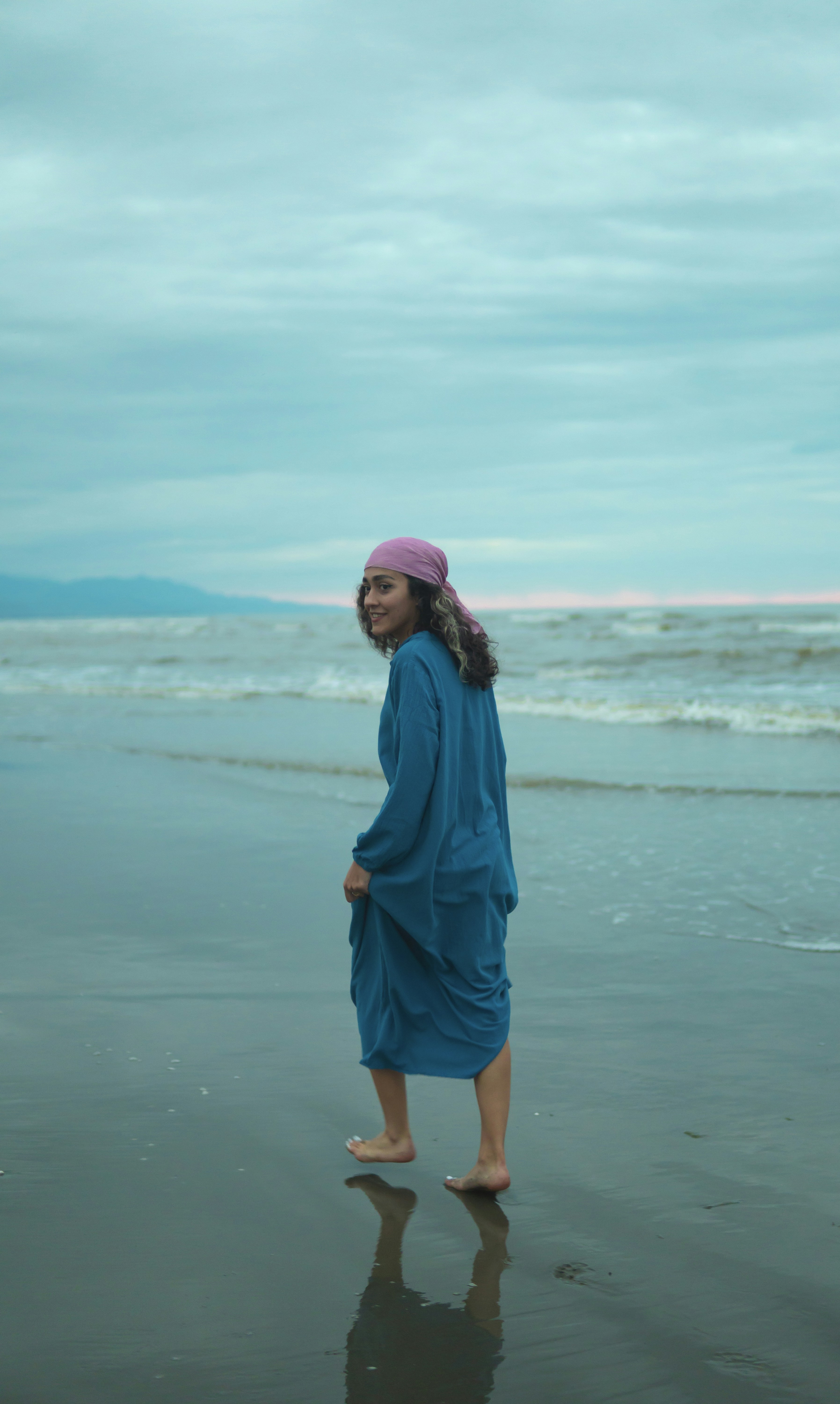 a woman standing on a beach next to the ocean