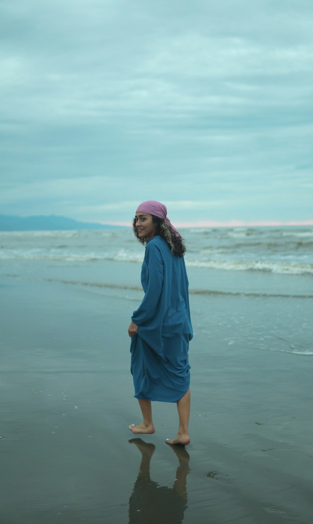 a woman standing on a beach next to the ocean