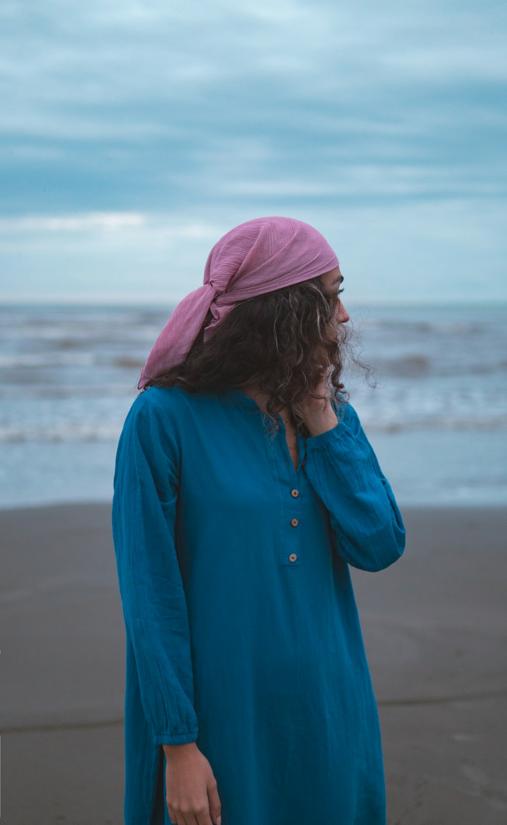 a woman in a blue dress standing on a beach