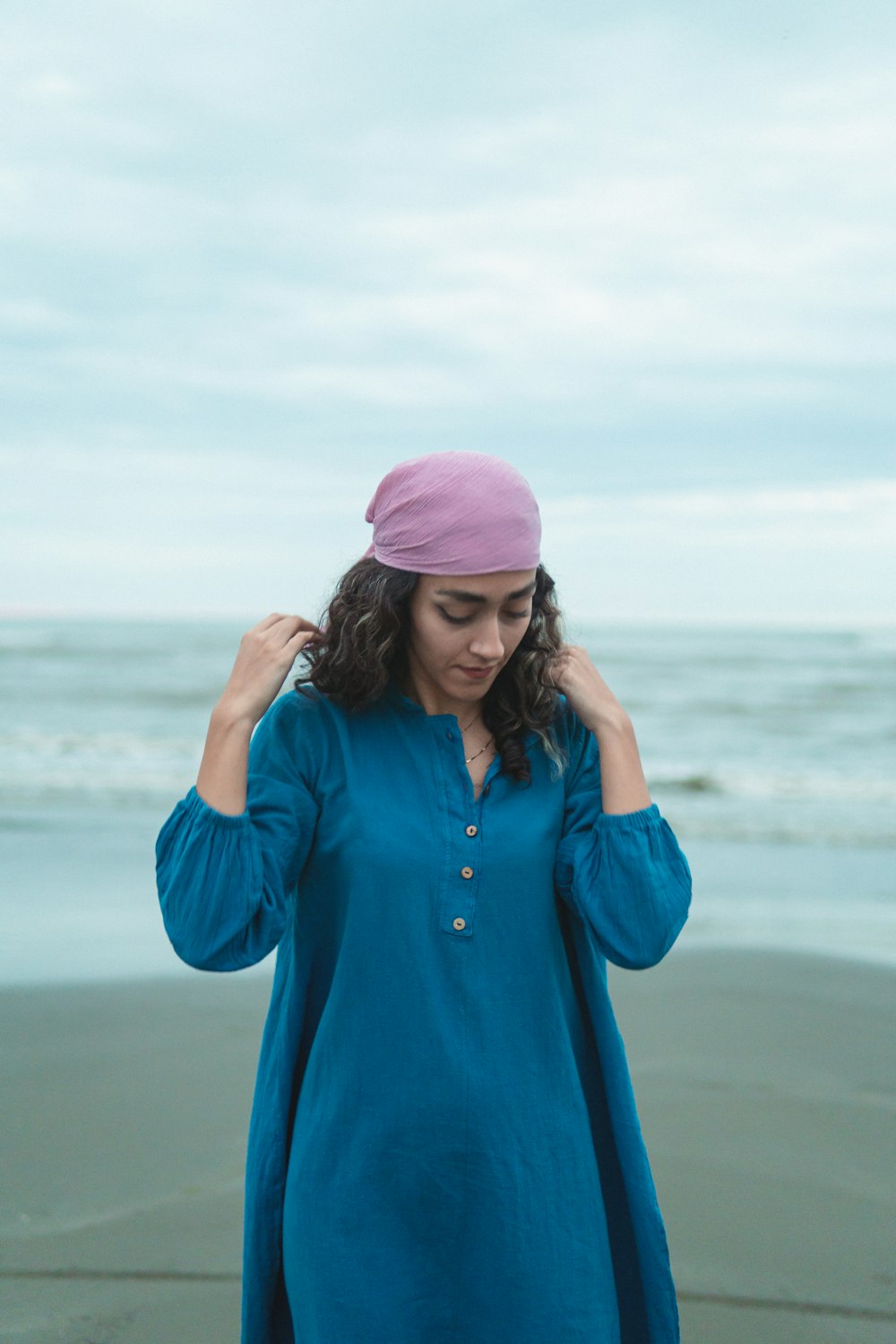 a woman standing on a beach wearing a blue dress