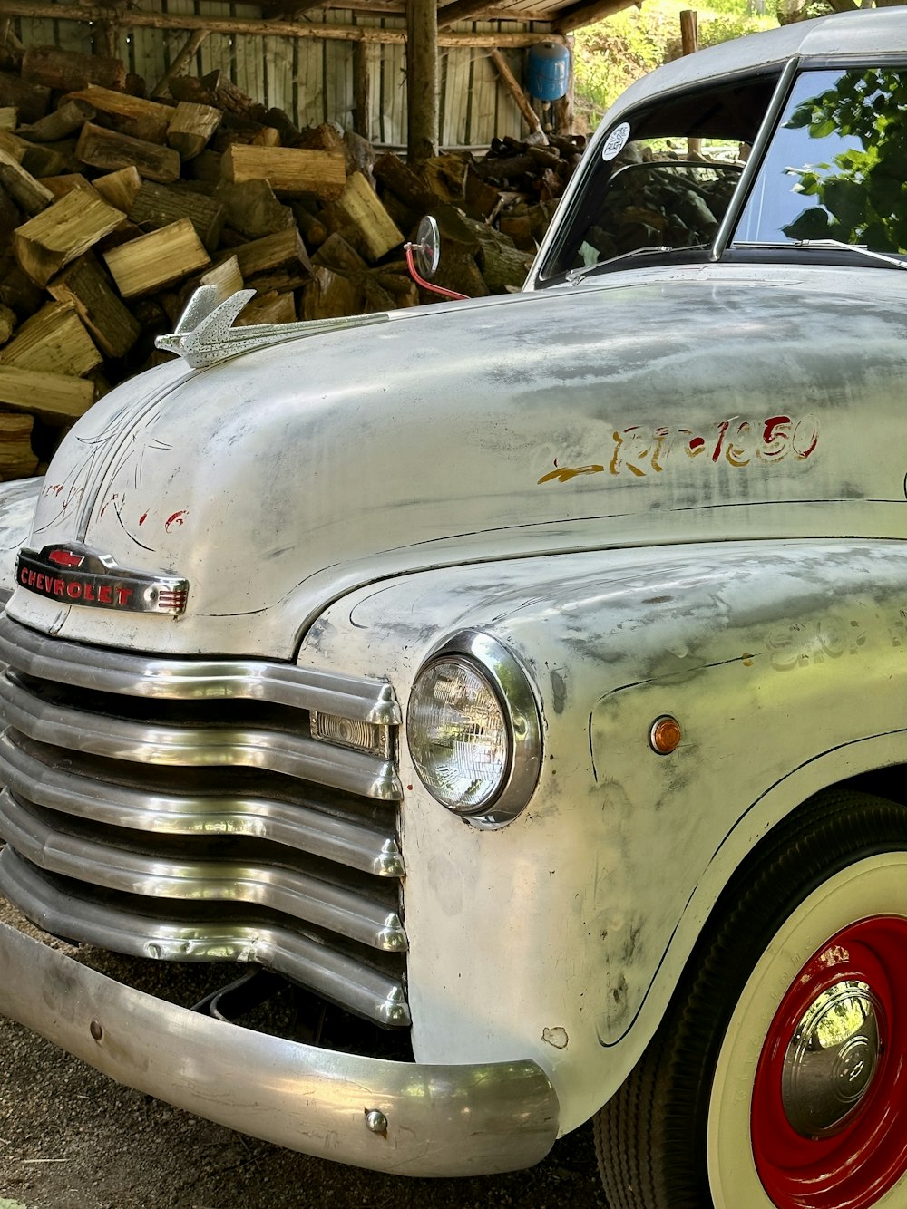 um caminhão velho estacionado ao lado de uma pilha de madeira