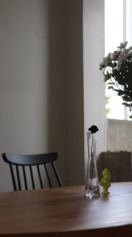An elegant wooden flower arrangement displayed on a cozy wooden table by a sunlit window.