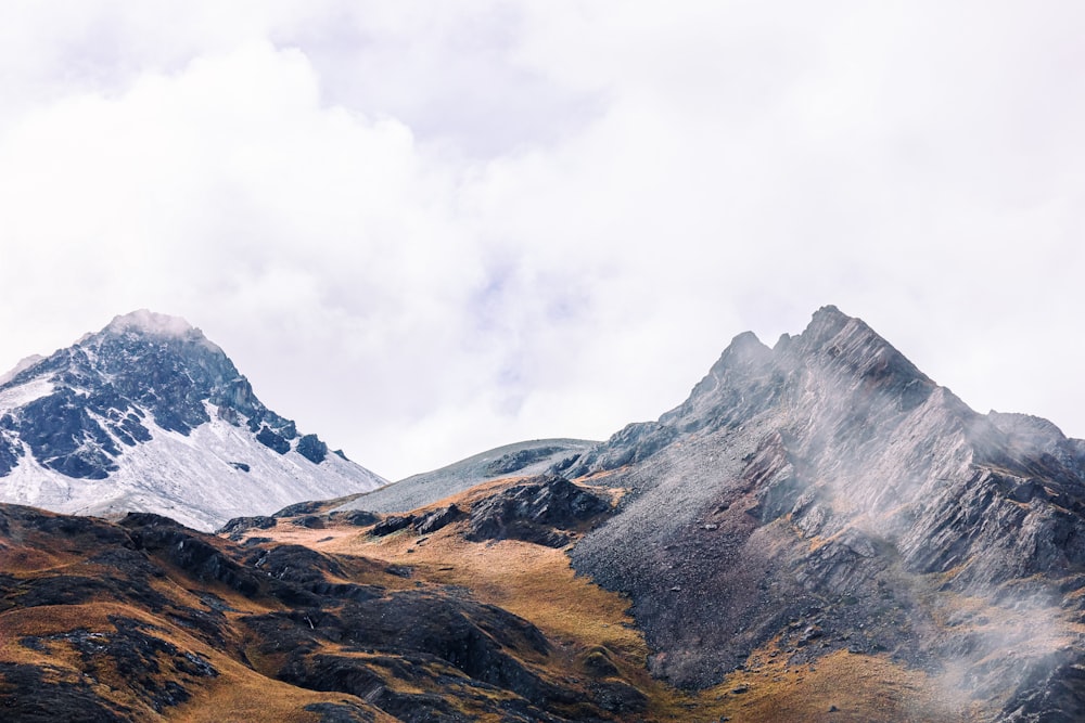 a mountain range covered in snow and brown grass