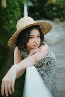 a woman wearing a hat leaning on a rail