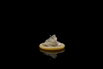 A hand holding a transparent ultra-thin condom against soft natural light