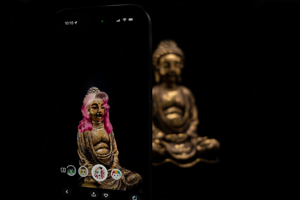 a cell phone with a gold buddha statue on it