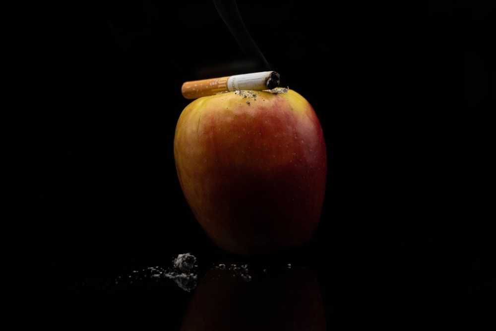 an apple with a cigarette sticking out of it
