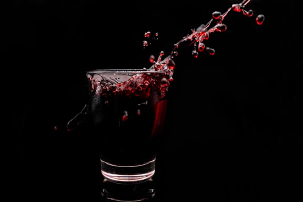 An artistic shot of a glowing red liquid splash frozen mid-air on a pure black background.