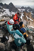 Group of climbers resting on a ledge, sharing smiles and gear.
