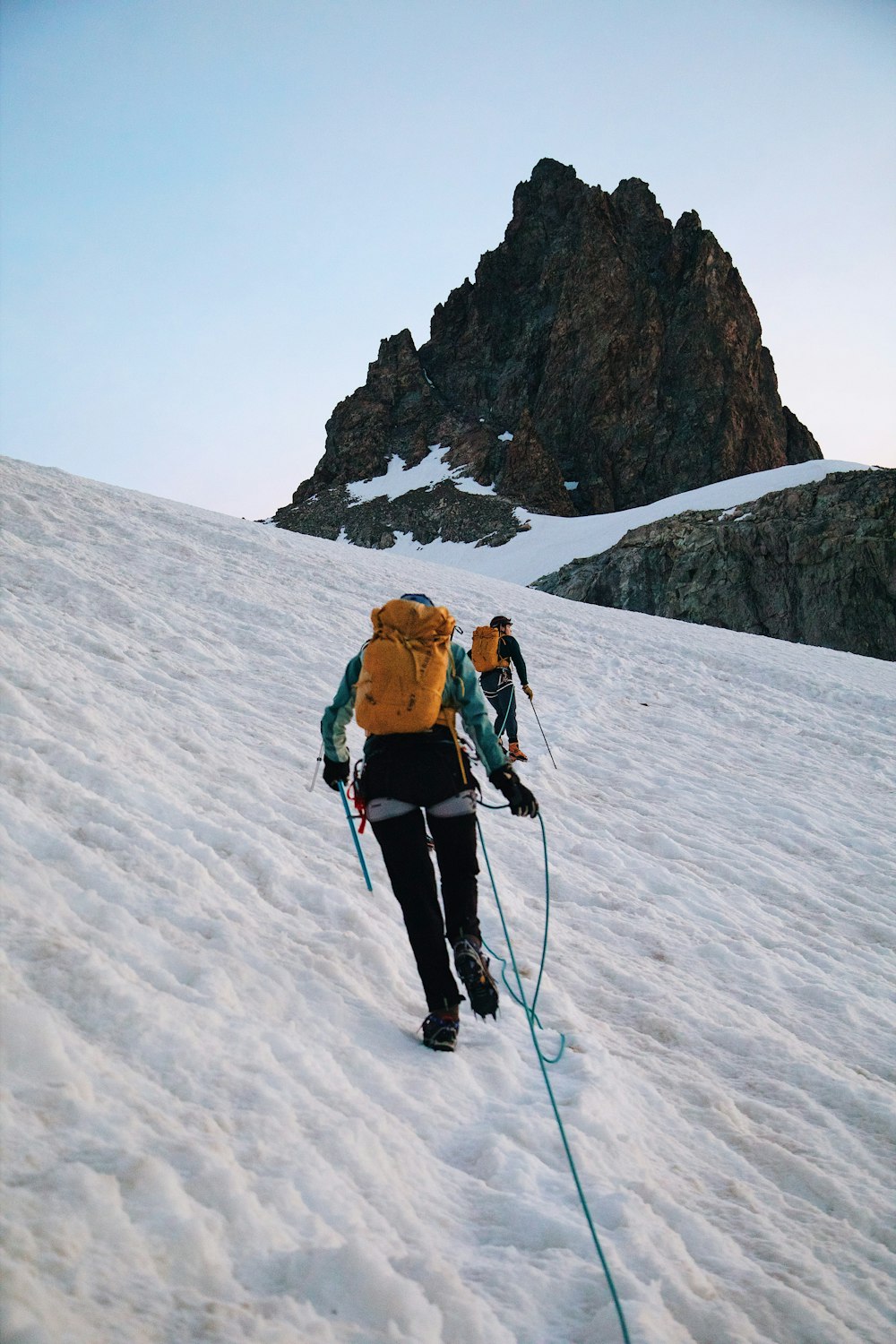 a couple of people walking up a snow covered slope