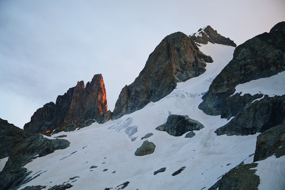 a snow covered mountain with rocks and a sky background