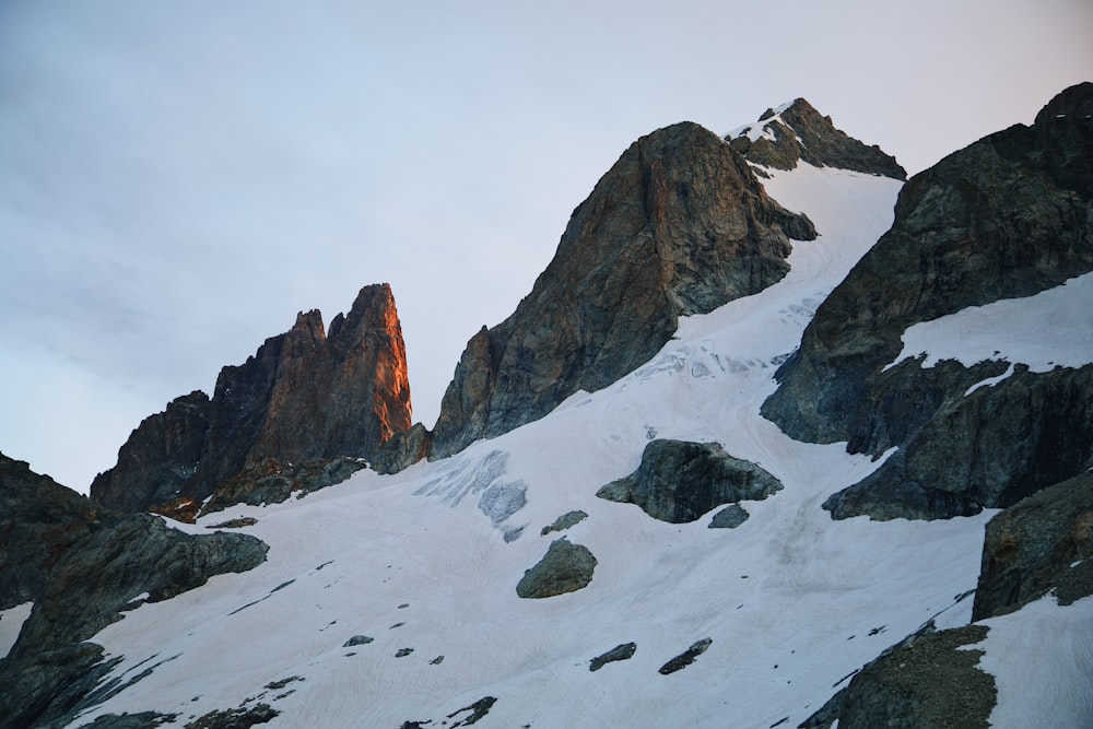 Una montagna coperta di neve con rocce e uno sfondo del cielo