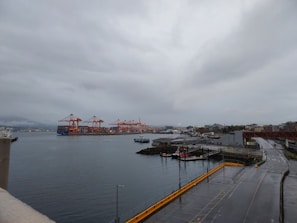 Workers inspecting imported building materials at the docks under cloudy sky