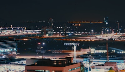 Aerial view of a busy airport with aircraft and control towers in the background.