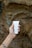A hand with a tattoo on the wrist is holding a tube of hand cream labeled 'PLANTADEA BIO CREMA MANI' against a textured rocky background.