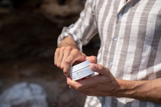 A smiling person holding a dseyia llc hand cream tube with natural ingredients in the background.