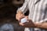 Close-up of hands holding a natural beauty product with soft sunlight in the background.
