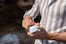 Close-up of a hand holding a glowing jar of Bright Moon Cosmetic cream against a natural background.