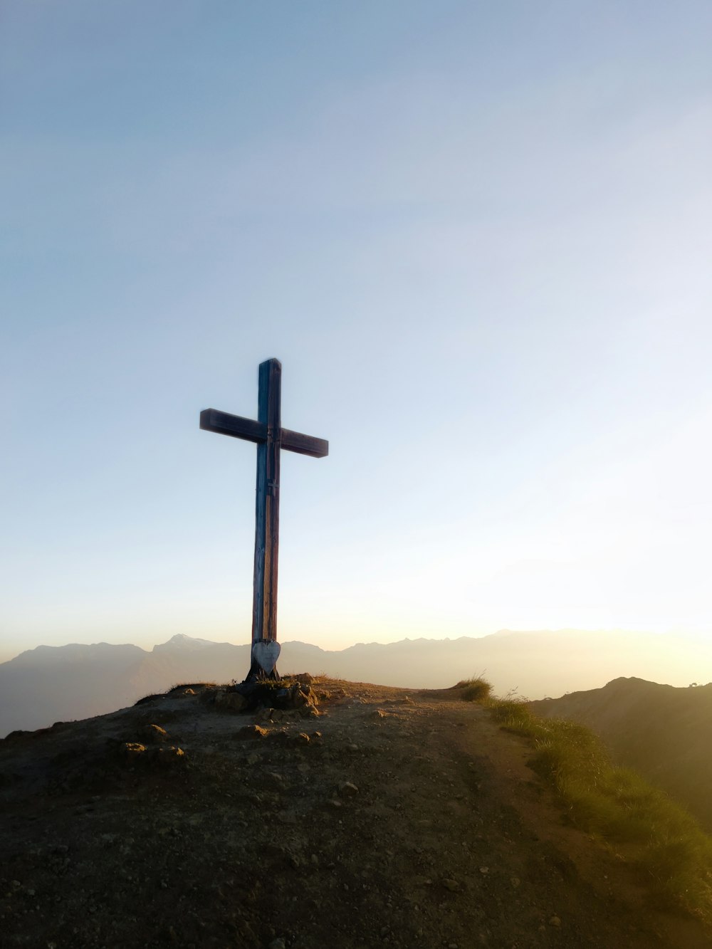 a cross on top of a hill with a sky background