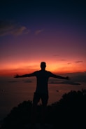 a man standing on top of a hill with his arms outstretched