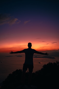 a man standing on top of a hill with his arms outstretched