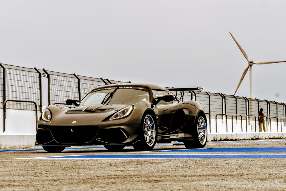 a brown sports car driving past a wind turbine