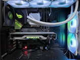 A high-end gaming or performance PC interior equipped with RGB lighting and multiple cooling fans. The graphics card prominently displayed is a GeForce RTX model, with branding visible. The setup includes neatly managed cables and a liquid cooling system.